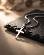 Silver cross pendant necklace styled on a dark surface