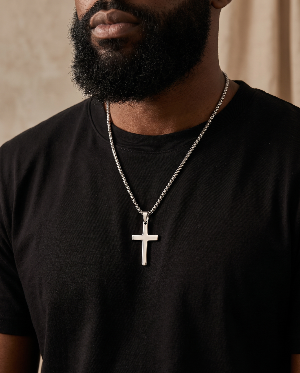 Man wearing a silver cross pendant necklace on a box-link chain