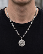 Man wearing a silver compass pendant necklace with a black T-shirt